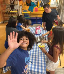 Trinity-Trust-Left-web A group of middle schoolers bakes brownies around a table.