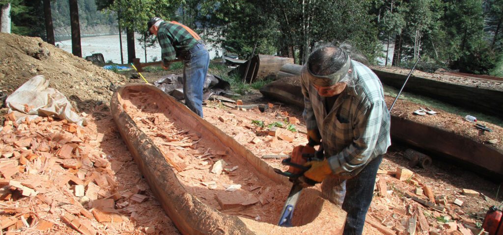 two men working on a native wood tree boat