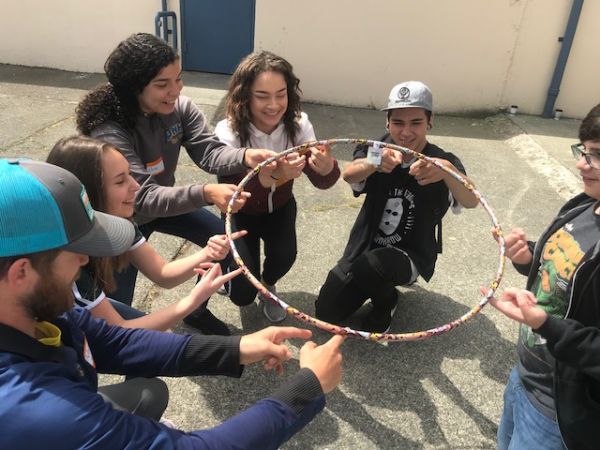 kids sitting in a circle with a hulahoop