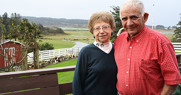 couple standing in front of a farm background