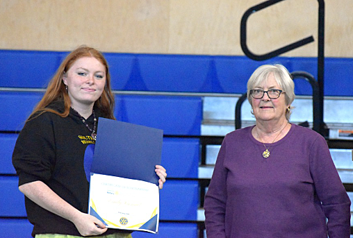 A young woman receives a certificate from an elder at a scholarshp ceremony.