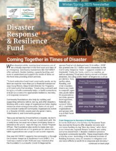 Person in firefighting gear stands  in front of trees burning