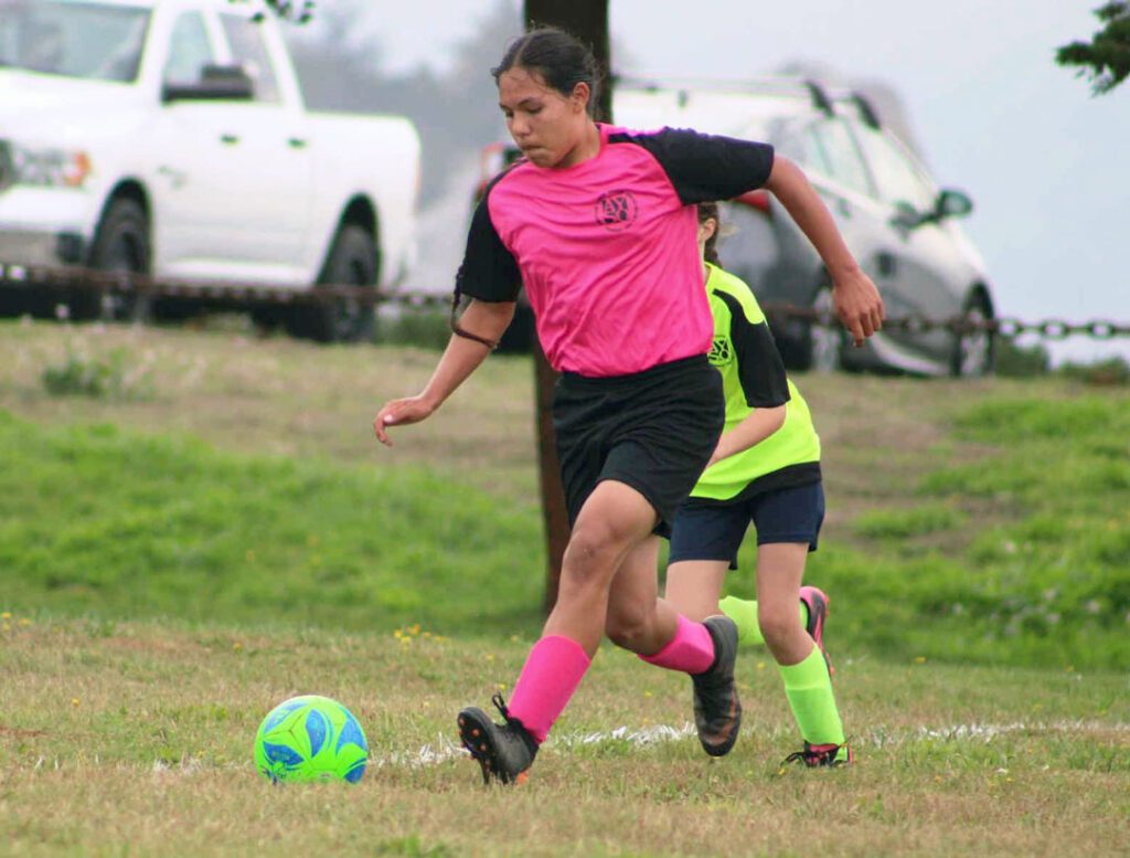 09_DAF_Soccer-web2 A young girl in a pink soccer jersey plays soccer.